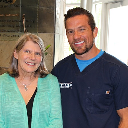 Dr. Keller in blue scrubs talks with a patient about sedation dentistry